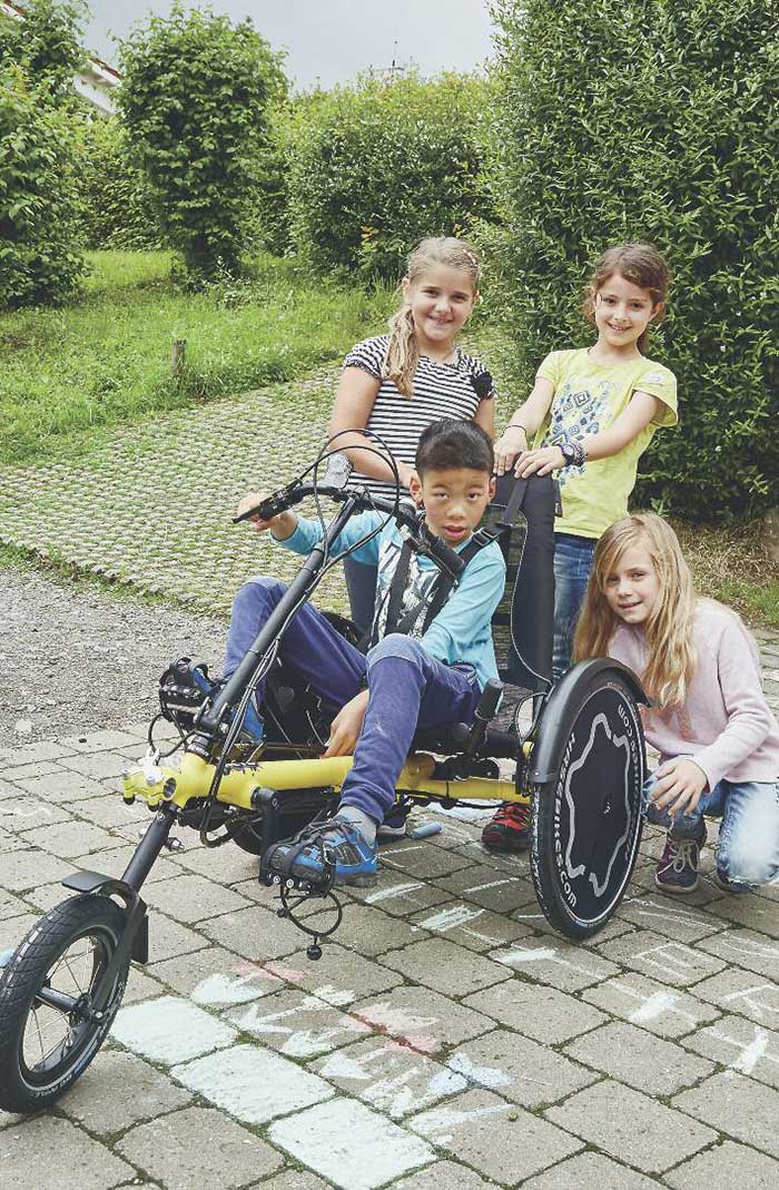 boy and friends posing with a hase trets kids recumbent trike